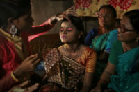 On her wedding day Shorbari, 13, is dressed by her mother, aunt and sisters in a traditional bridal sari, new jewellery and make-up. Gauri, her mother, is particularly keen to make the best impression on the 41 year-old groom whom no-one in the family has yet met and to whom the arrangement was proposed through a paid marriage broker. Older, affluent grooms are seen as saving graces for those with daughters in poor, rural families; the hope is that early marriage can offer a new life of financial stability and good repute. In reality, however, young brides are often abused and neglected by older husbands, left to bear the burden of child-rearing single-handedly while working as an effective servant in an in-law’s family home.