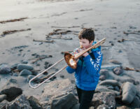 Simún Jacobsen playing trombone on the beach of Sandavágur, Faroe Islands.
